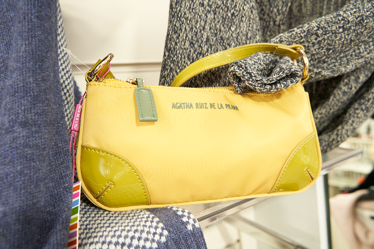 Bolso amarillo con detalles verdes de Agatha Ruiz de la Prada expuesto en una boutique.