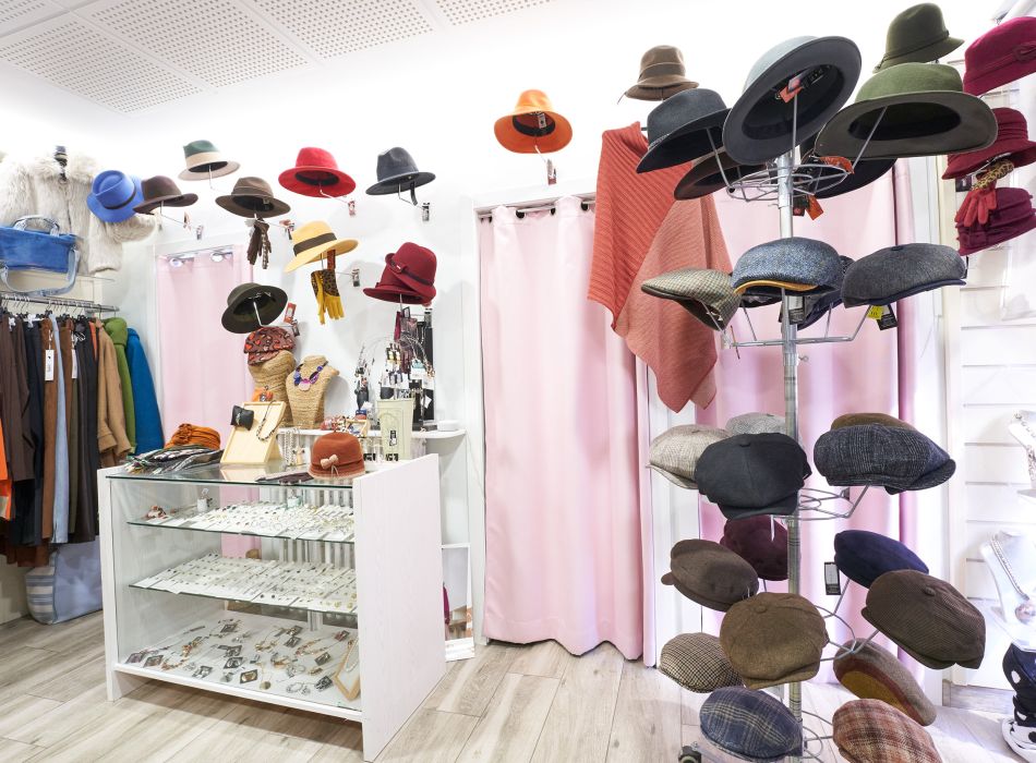 Interior de una boutique con sombreros, bisutería y ropa de invierno cuidadosamente expuestos.