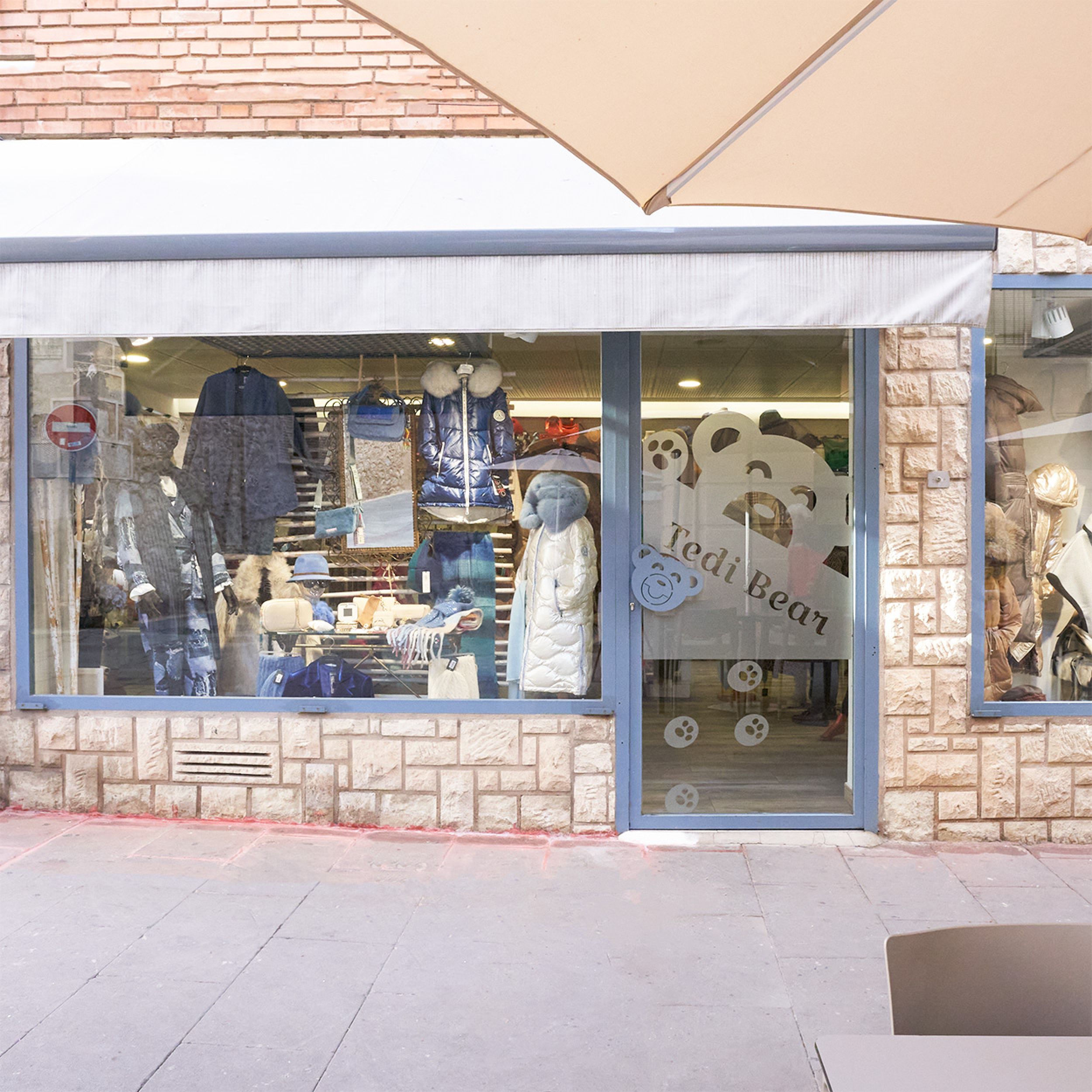 Fachada del escaparate principal de la tienda Tedi Bear con prendas de invierno y decoración en tonos azules.