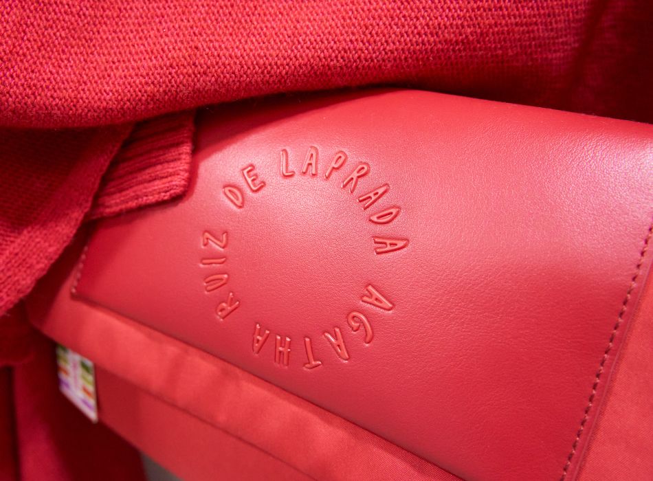 Detalle de un bolso rojo con el nombre "Agatha Ruiz de la Prada" grabado en relieve.