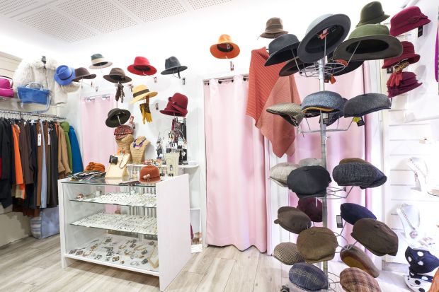 Interior de una boutique con sombreros, bisutería y ropa de invierno cuidadosamente expuestos.